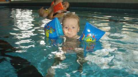 Kleinkind mit Schwimmhilfen im Wasser